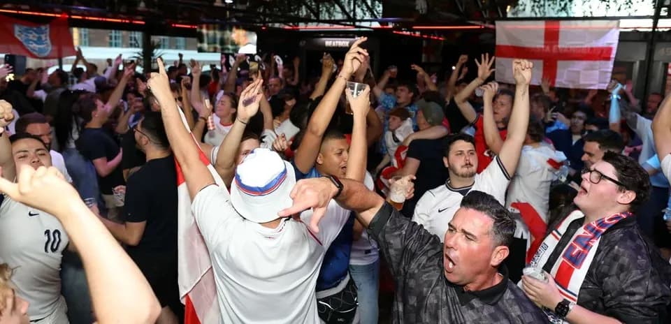 Aficionados celebrando en bar con banderas de Inglaterra