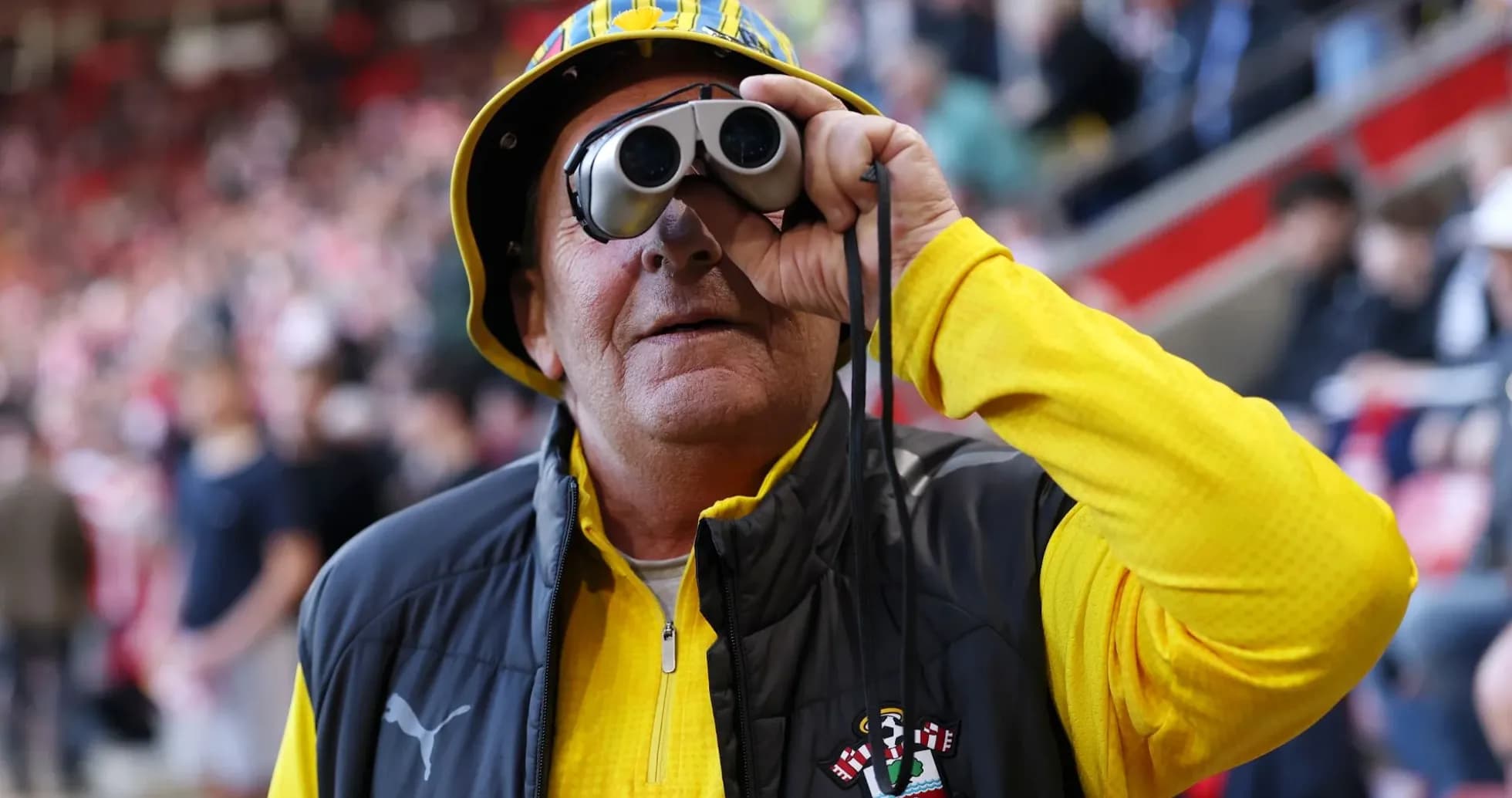 A fan with binoculars at a football match