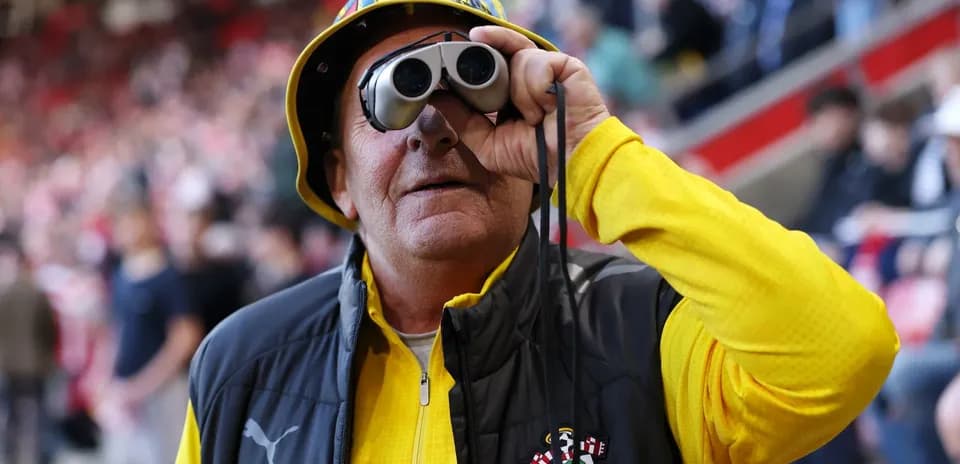 A fan with binoculars at a football match