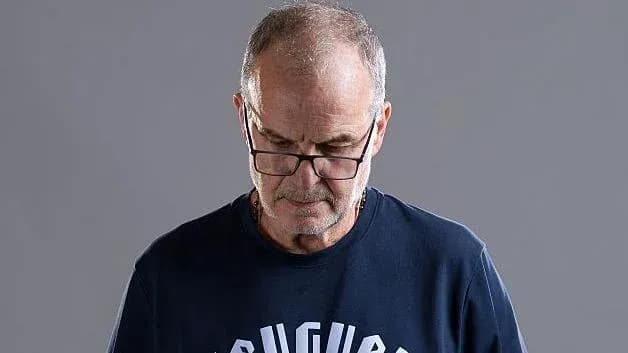 Hombre con gafas mirando hacia abajo en fondo gris