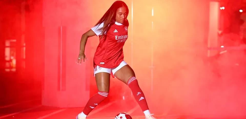 Jugadora de fútbol de Arsenal con balón en humo rojo