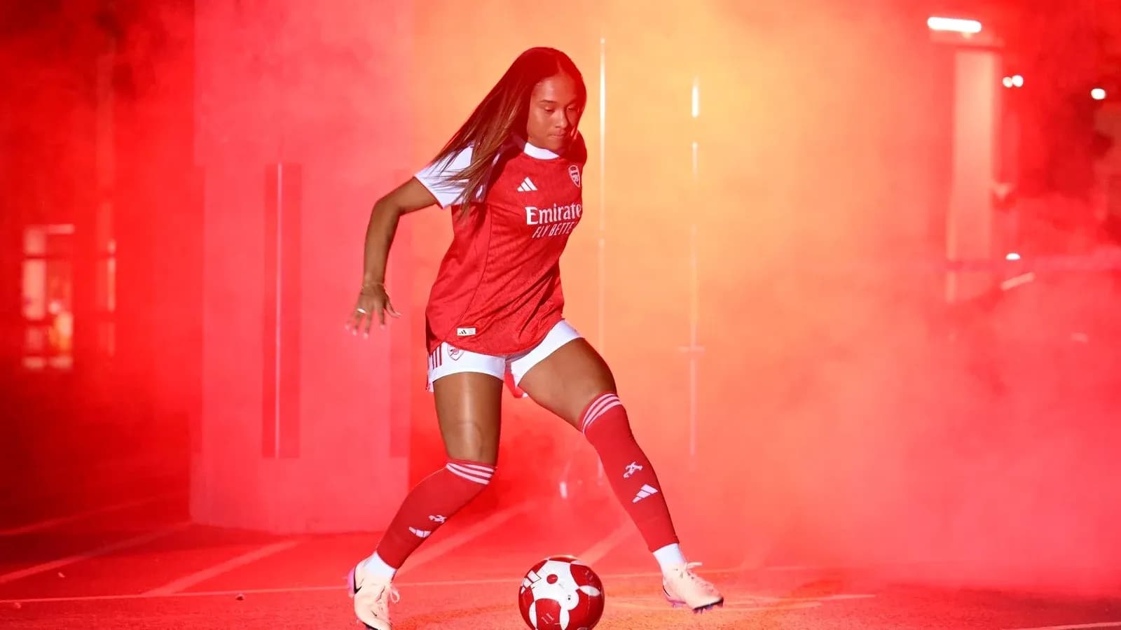 Jugadora de fútbol de Arsenal con balón en humo rojo