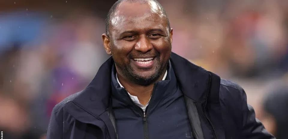 Entrenador sonriendo durante un partido en el estadio