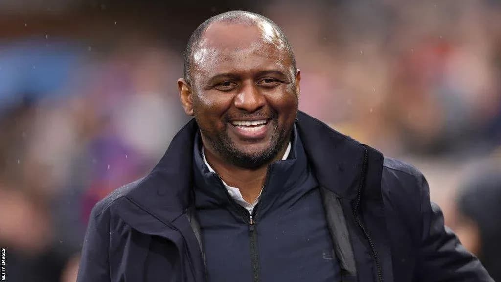 Entrenador sonriendo durante un partido en el estadio