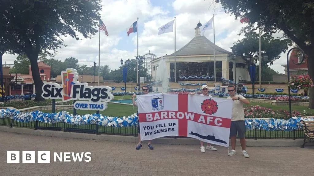 Dos aficionados sosteniendo una bandera de Barrow AFC en Six Flags