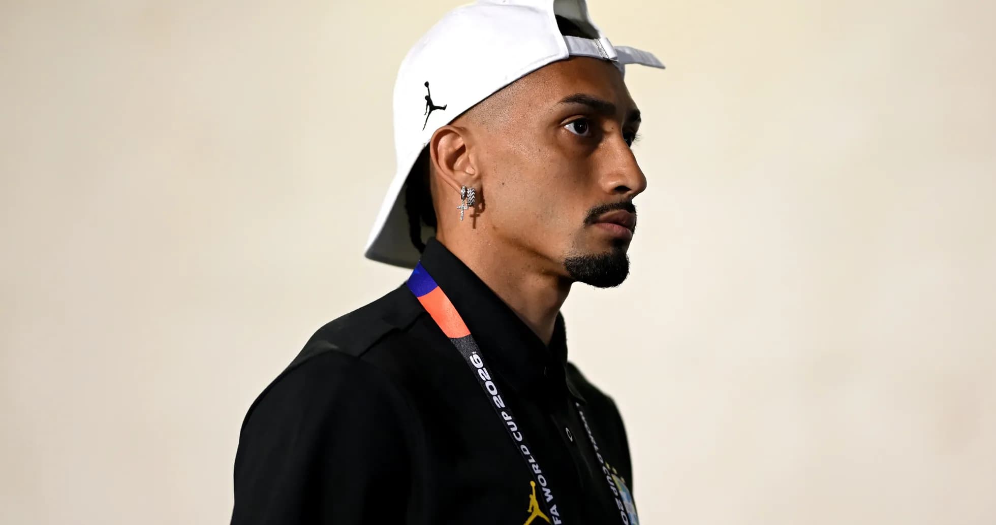 Jugador con gorra blanca y camiseta negra en pasillo