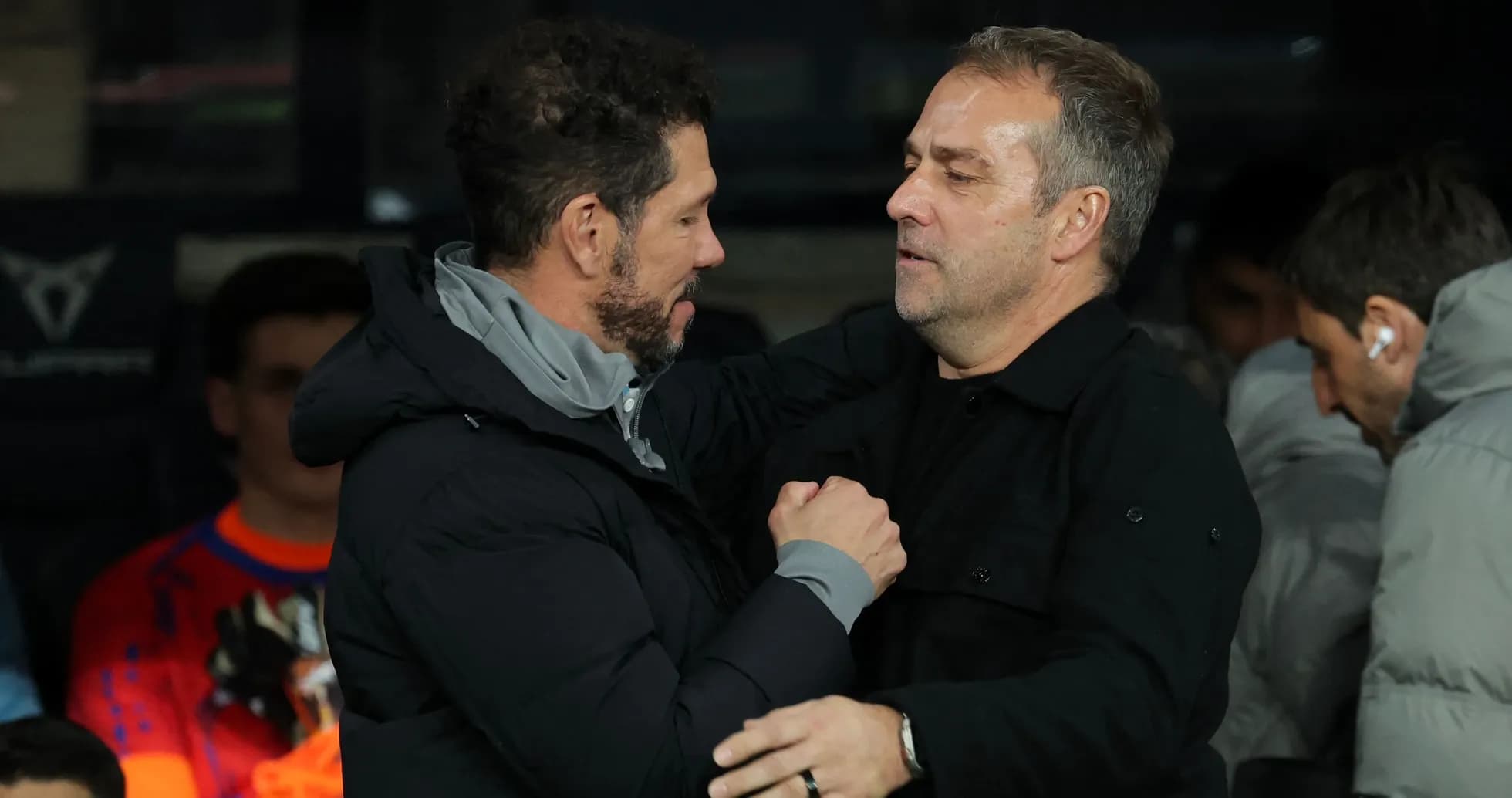Entrenadores saludándose en la banca durante el partido