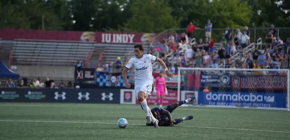 Jugador de Indy Eleven esquivando a oponente caído