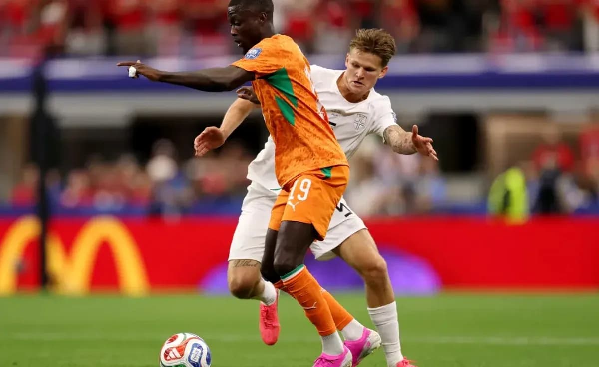 Jugador con camiseta naranja driblando mientras es marcado
