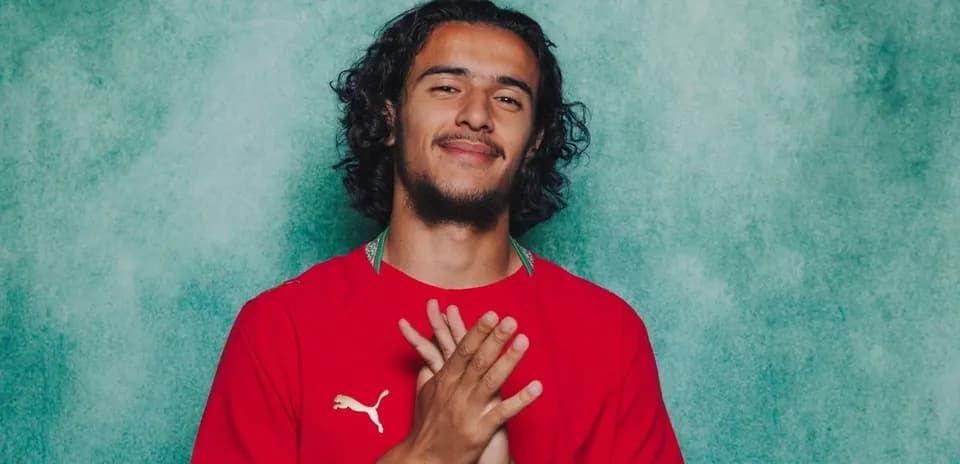 Jugador con camiseta roja posando frente a fondo verde