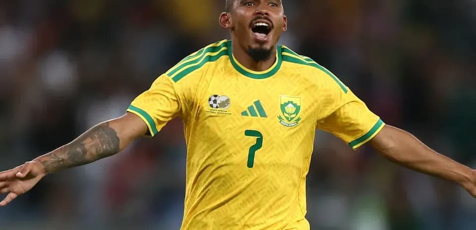 Jugador celebrando un gol con camiseta amarilla de Sudáfrica