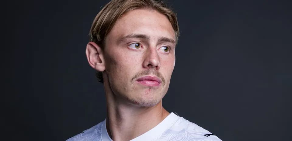 Jugador posando con camiseta blanca y fondo oscuro