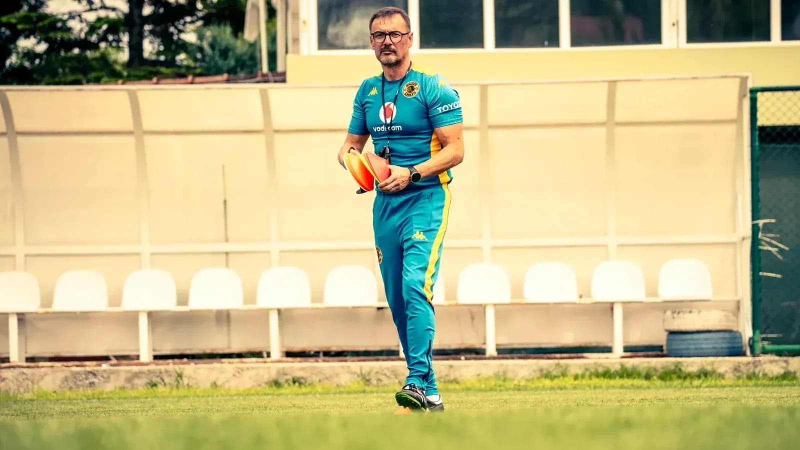 Entrenador caminando con conos en el campo