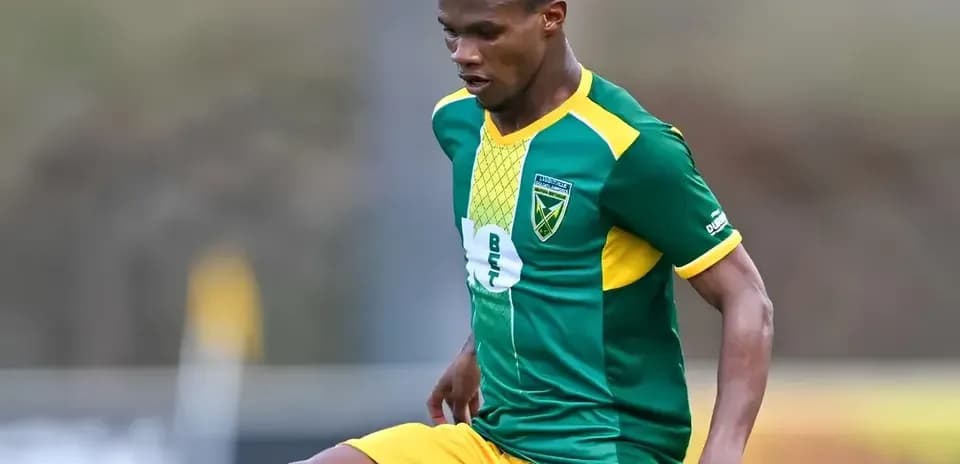 Jugador con uniforme verde y amarillo controlando el balón