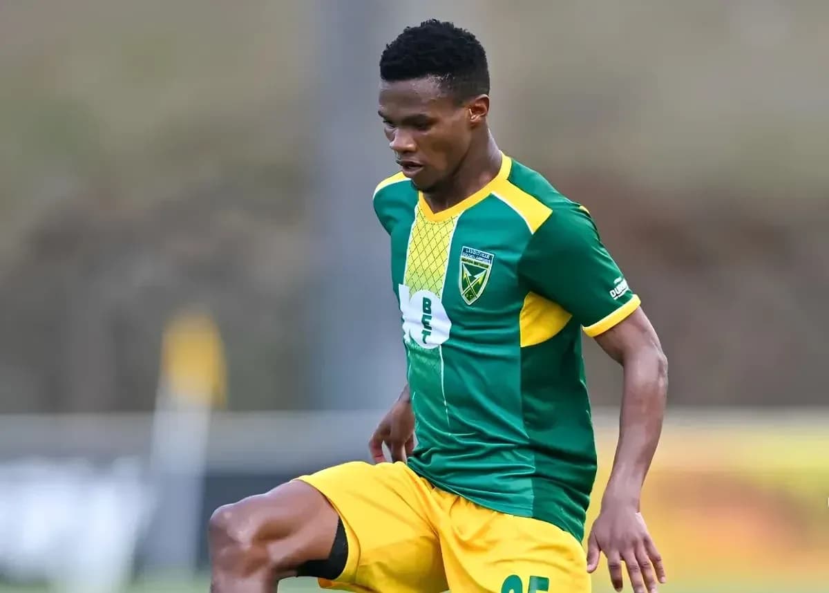 Jugador con uniforme verde y amarillo controlando el balón