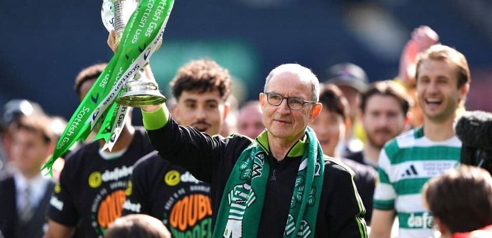 Entrenador levantando trofeo con bufanda en celebración