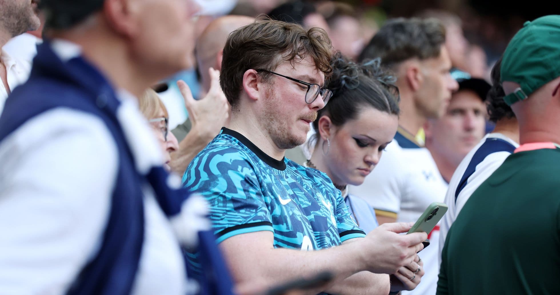 Espectadores mirando sus teléfonos en el estadio