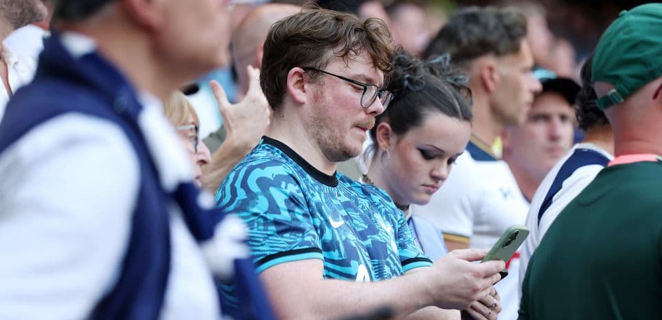Espectadores mirando sus teléfonos en el estadio