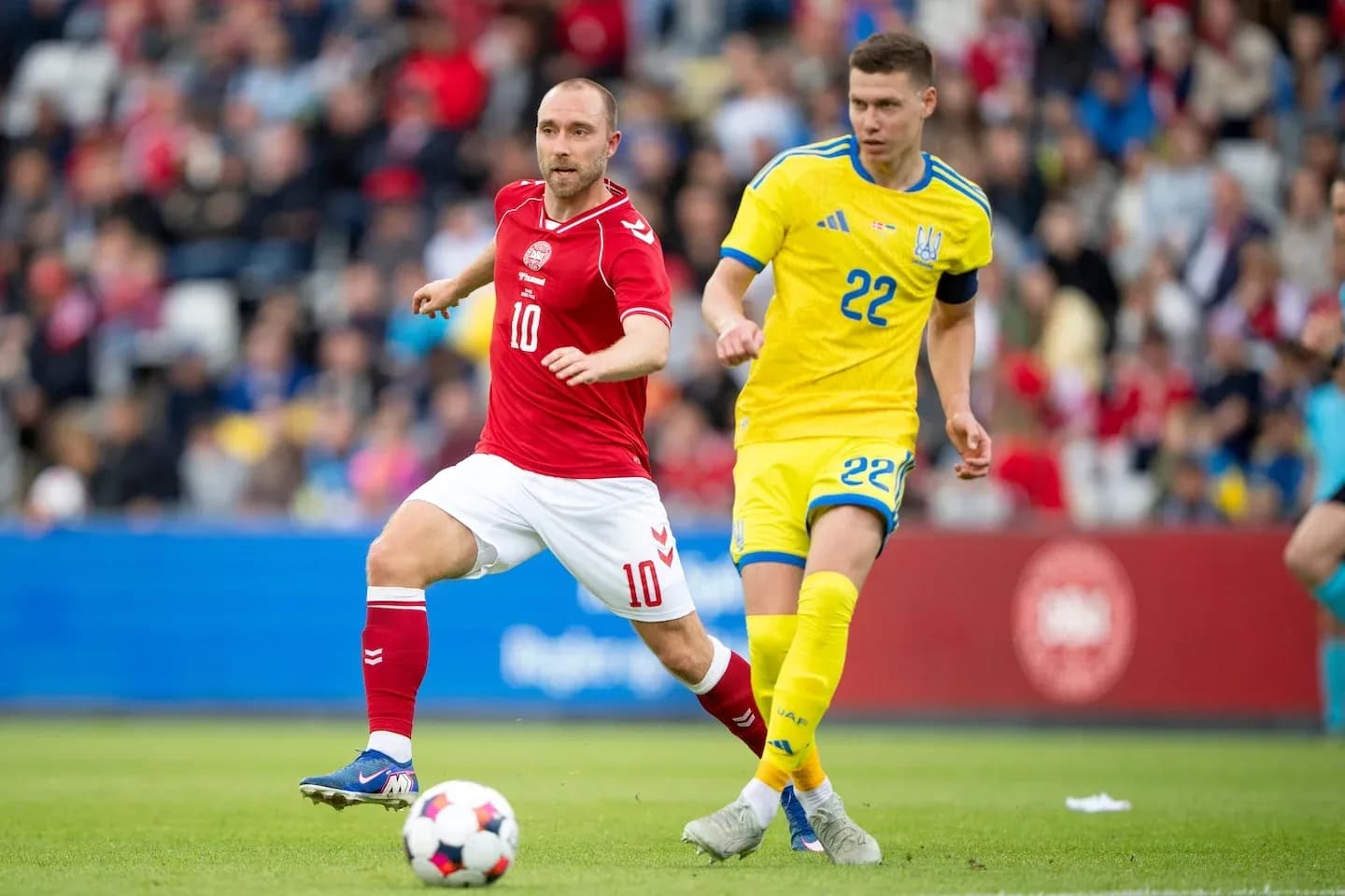 Christian Eriksen y jugador ucraniano corriendo tras el balón