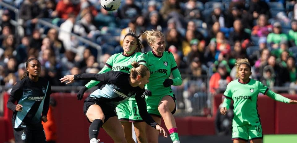 Jugadora cabeceando el balón en un partido de fútbol