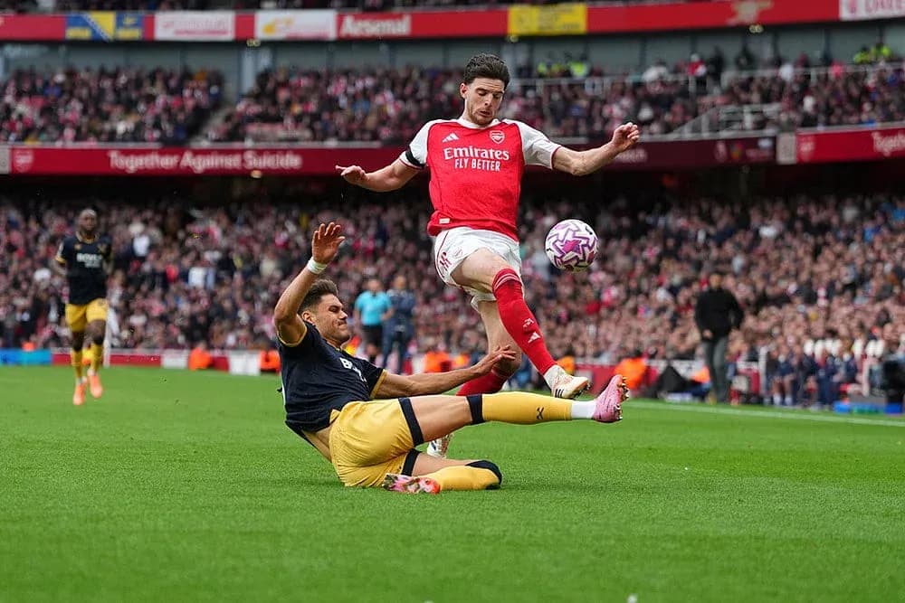 Jugador de Arsenal saltando sobre un oponente