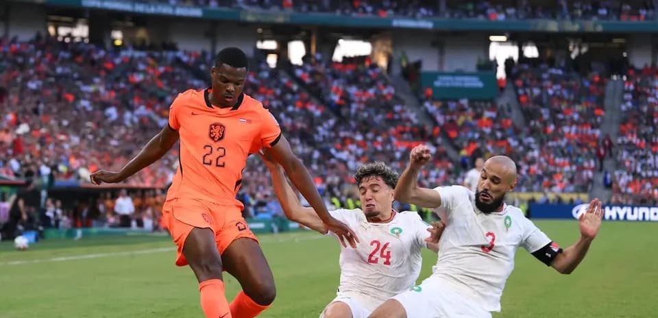 Jugador de Países Bajos desafiando a dos defensores marroquíes