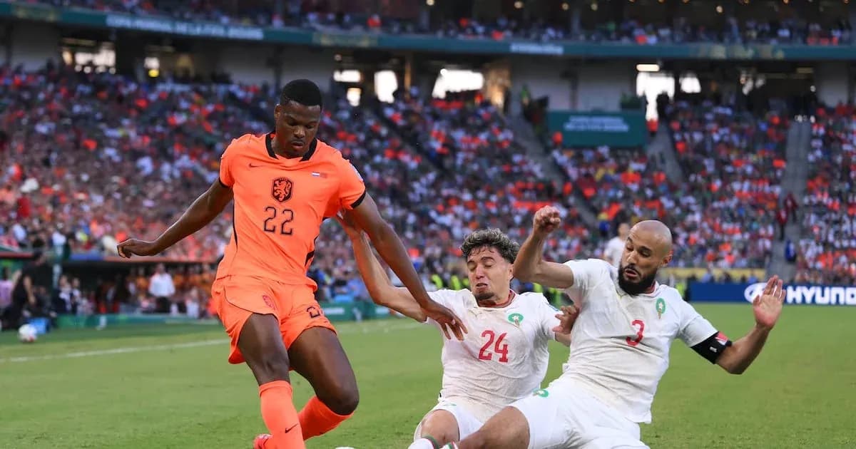 Jugador de Países Bajos desafiando a dos defensores marroquíes
