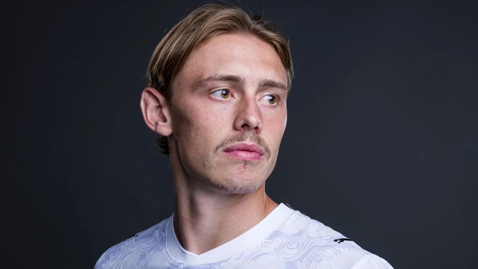Jugador posando con camiseta blanca y fondo oscuro Jugador posando con camiseta blanca y fondo oscuro